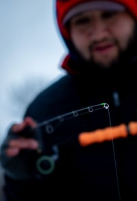 Lifestyle Image of an ice angler detecting a bite looking at the noodle rod tip 