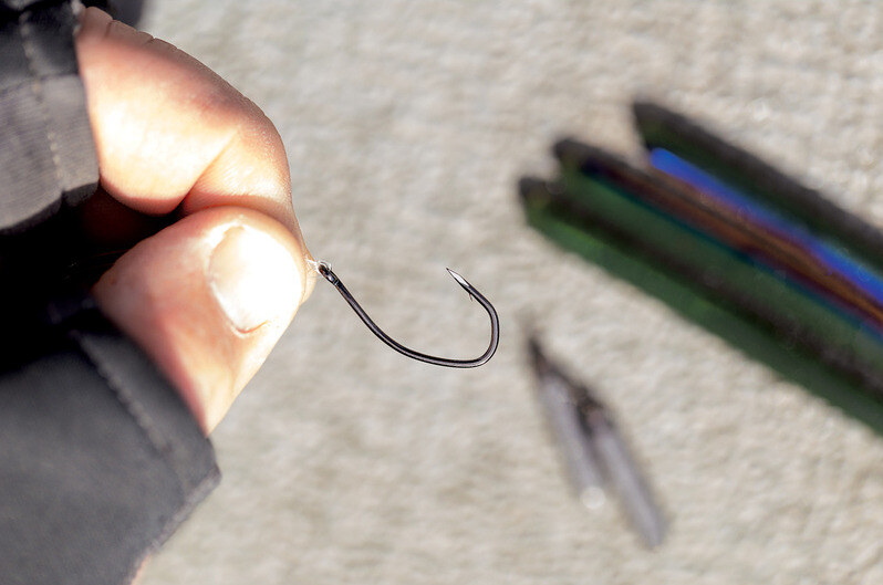 Angler holding a drop shot hook illustrating the sharpness of the Trokar point